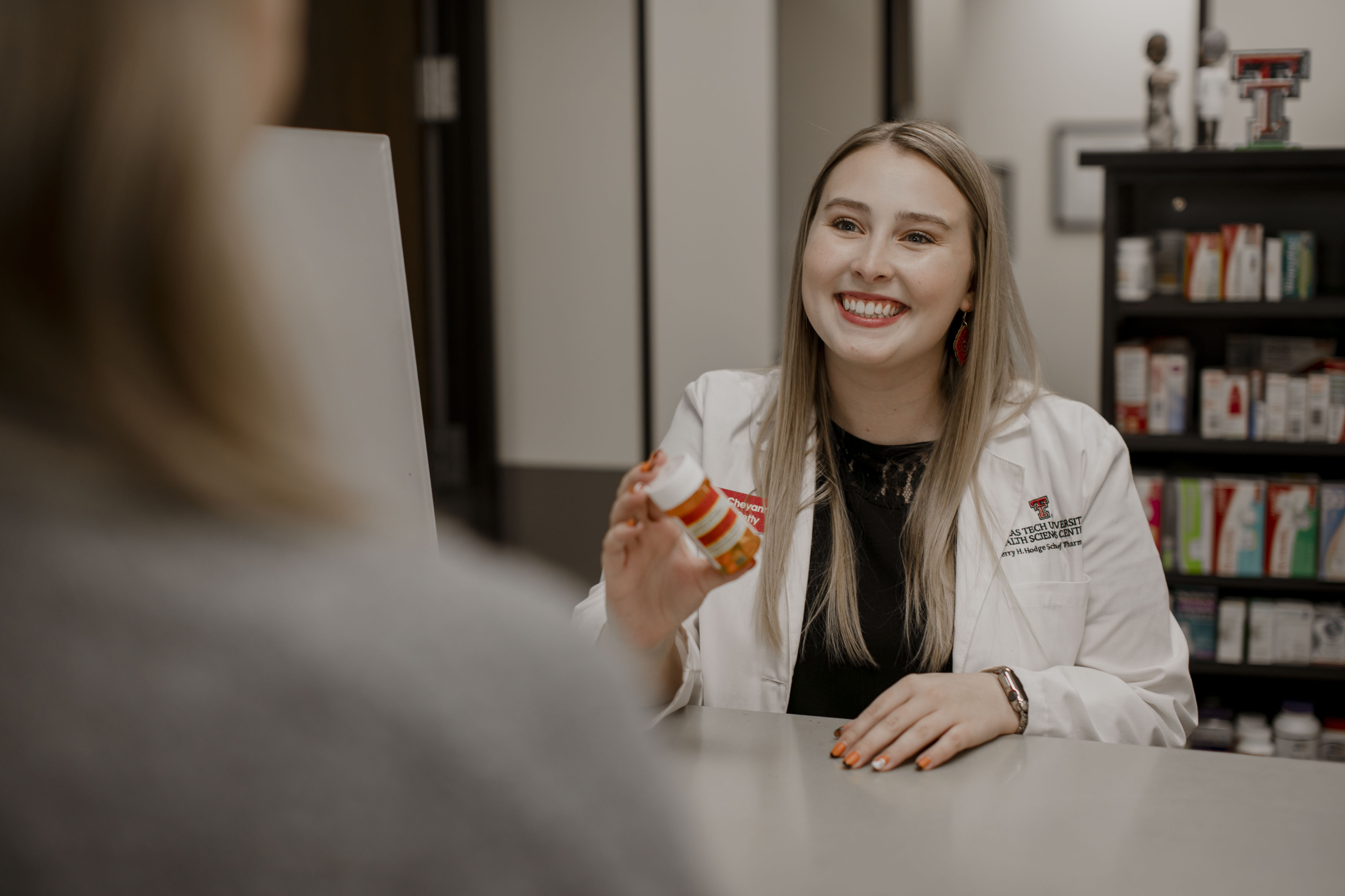 Pharmacist holding prescription bottle talking to patient