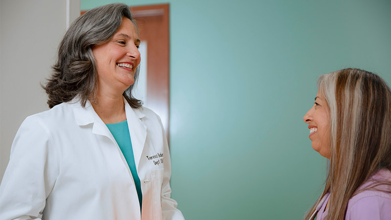 A woman discussing her health concerns with a doctor in a professional medical setting.