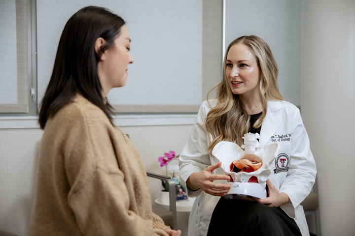 Provider smiling, holding a model for a patient