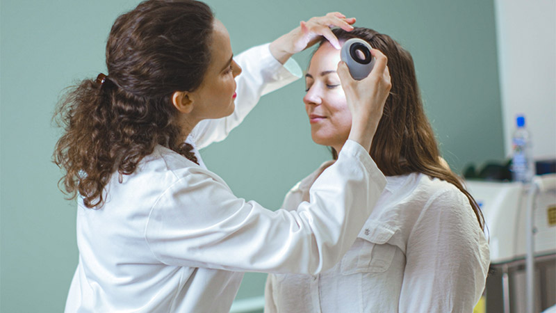 Female provider look at female patient forehead