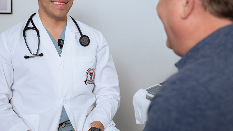 Provider sitting with patient in clinic room smiling
