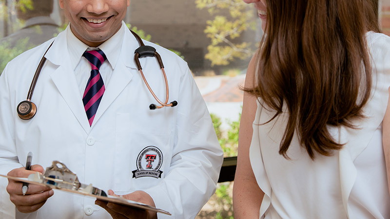 Provider sitting with patient in clinic room smiling