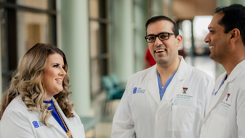Providers standing in a hall smiling at each other