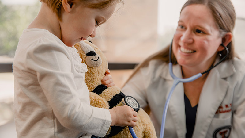 child using pediatrician's stethoscope on stuffed bear