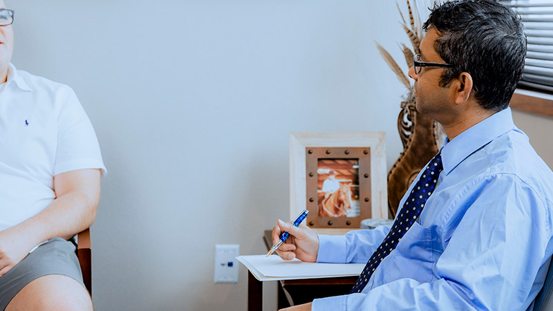 Provider sitting in chair with patient smiling in office setting