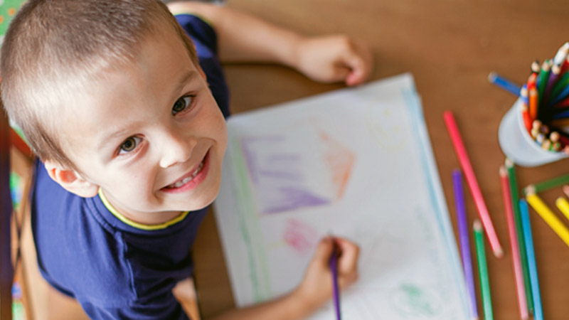 Child looking up while he colors a picture