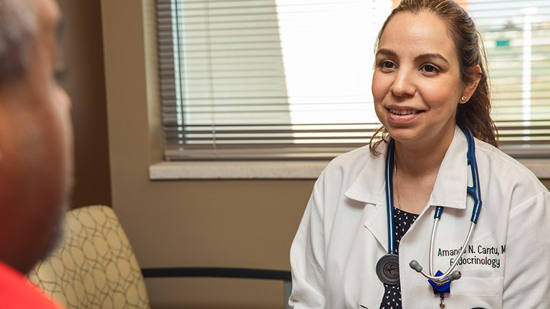 Provider sitting looking at a patient in a clinic room