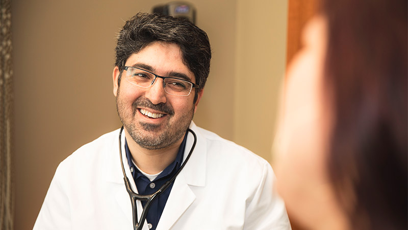 patient sitting in exam room with provider both smiling at each other